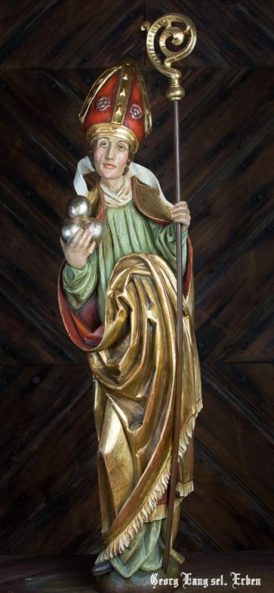Heilige Figur mit Stab, rotem mit Gold verzierten Kopfschmuck und reichhaltiger Robe.