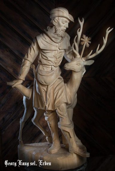 Statuette eines Jägers, der einen Hirsch mit großen Geweihen begleitet.
