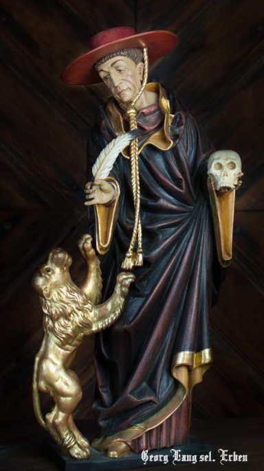 Eine Statue eines Heiligen mit einem Kind und einer Maske in der Hand.